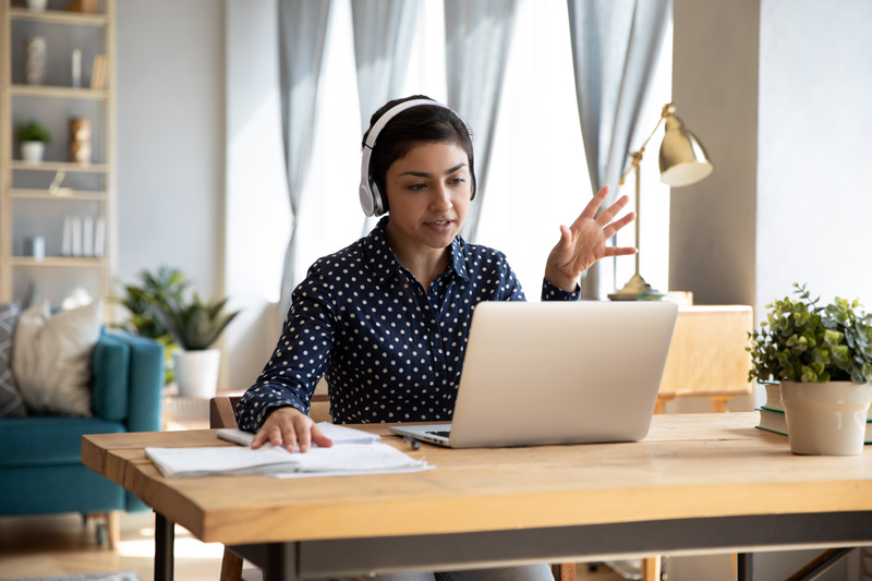 woman sitting at home office desk wearing headphones